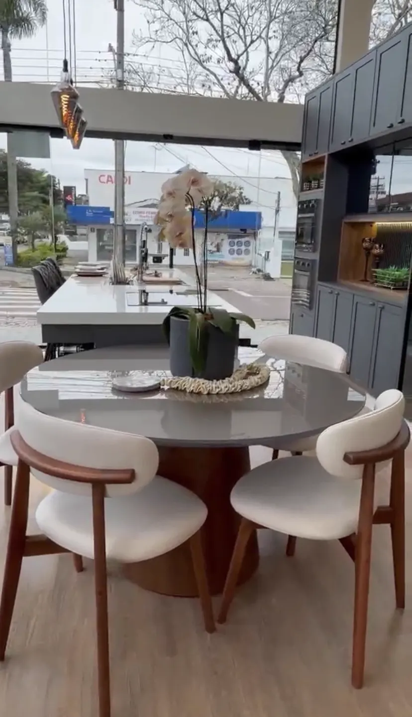 Mesa de jantar redonda com tampo cinza e cadeiras em madeira e estofado claro