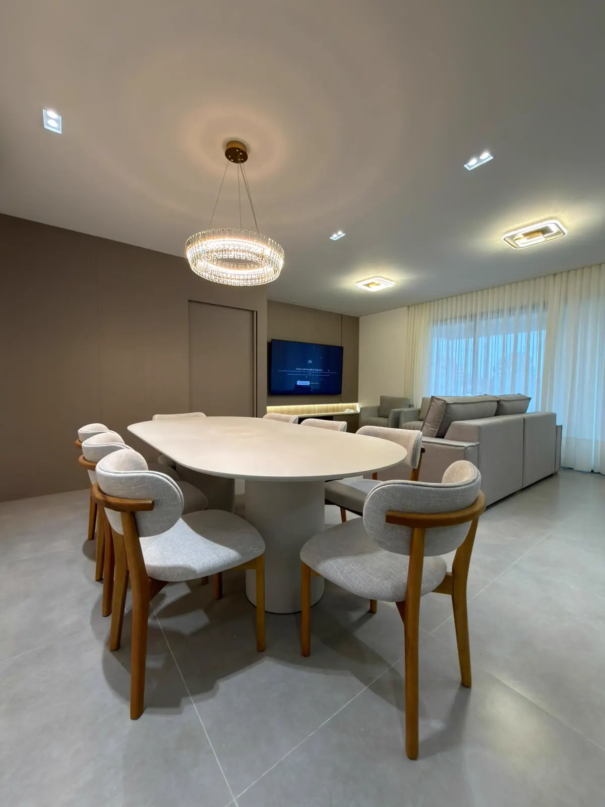 Cadeiras estofadas com estrutura de madeira ao redor de mesa oval em sala de jantar
