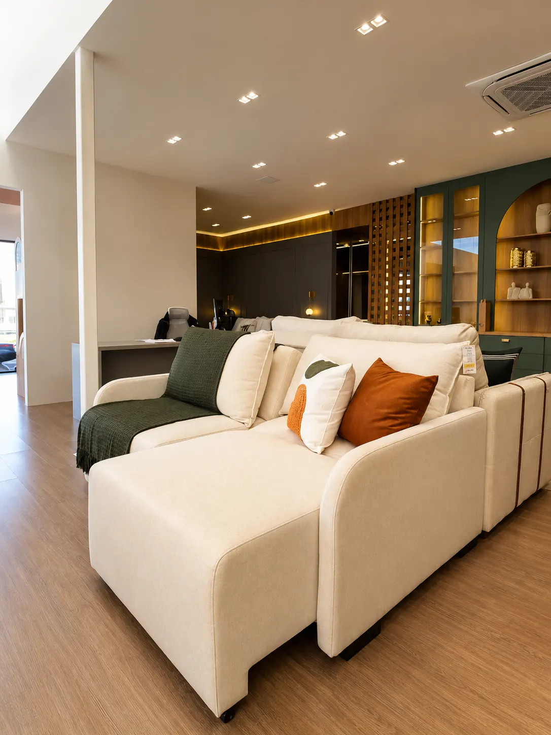 Sofá retrátil off-white com chaise e almofadas em ambiente do showroom Real Design